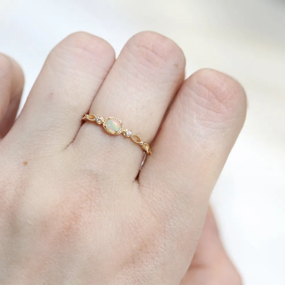 Model wearing a delicate vintage gold opal ring on index finger with milgrain bezel and openwork band.