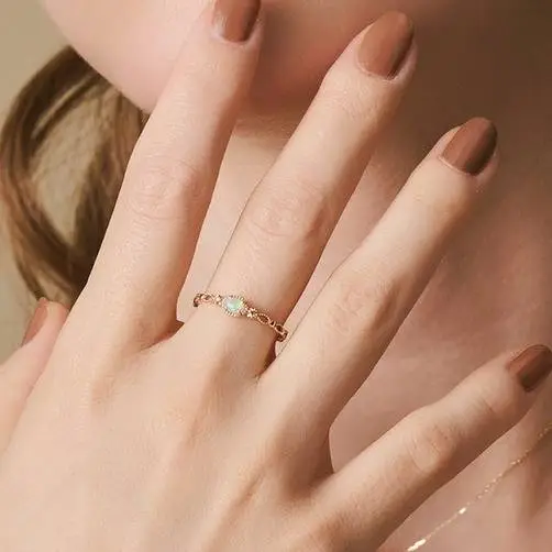 Model wearing a delicate vintage gold opal ring on index finger with milgrain bezel and openwork band.