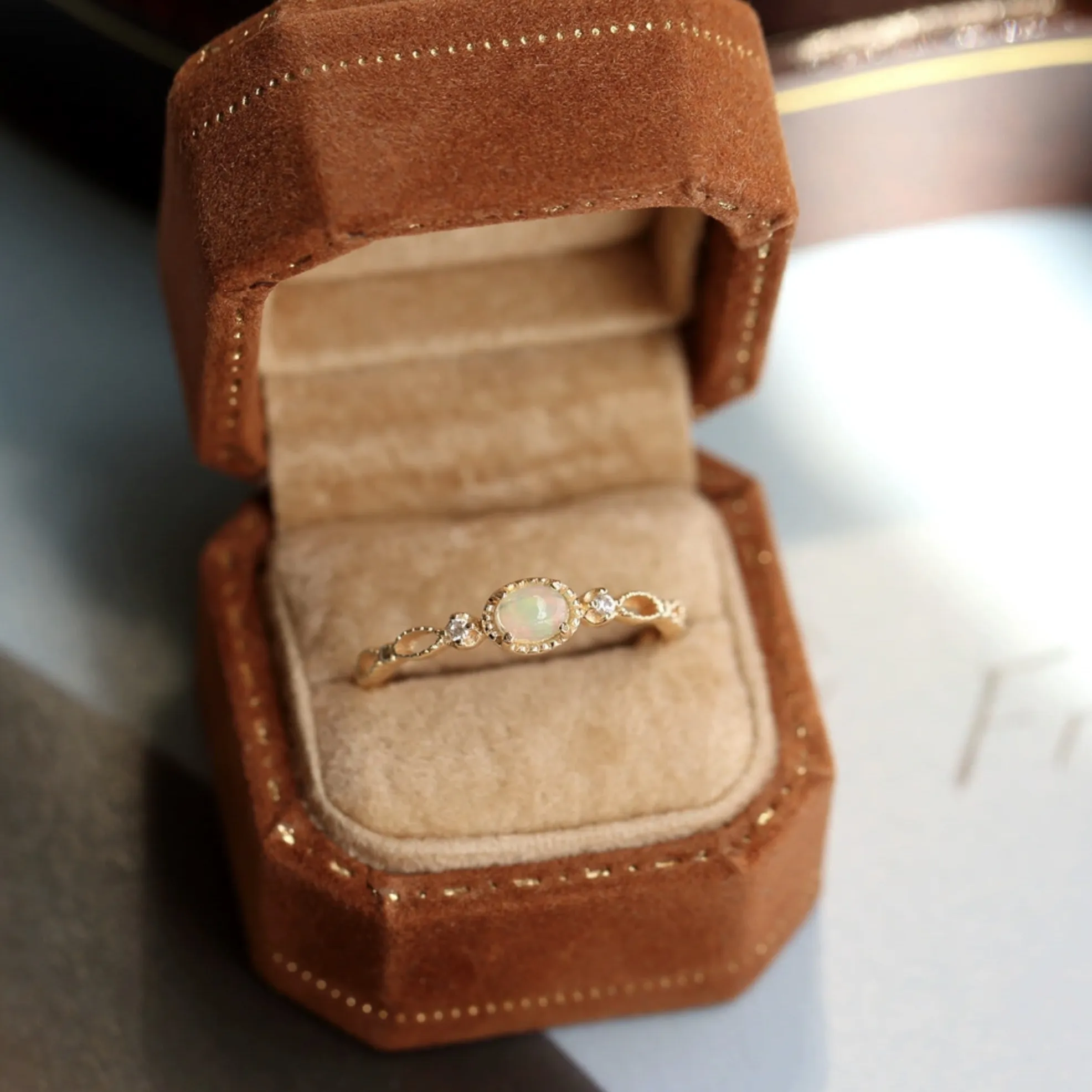 Vintage gold opal ring resting inside an open brown velvet hexagonal ring box.