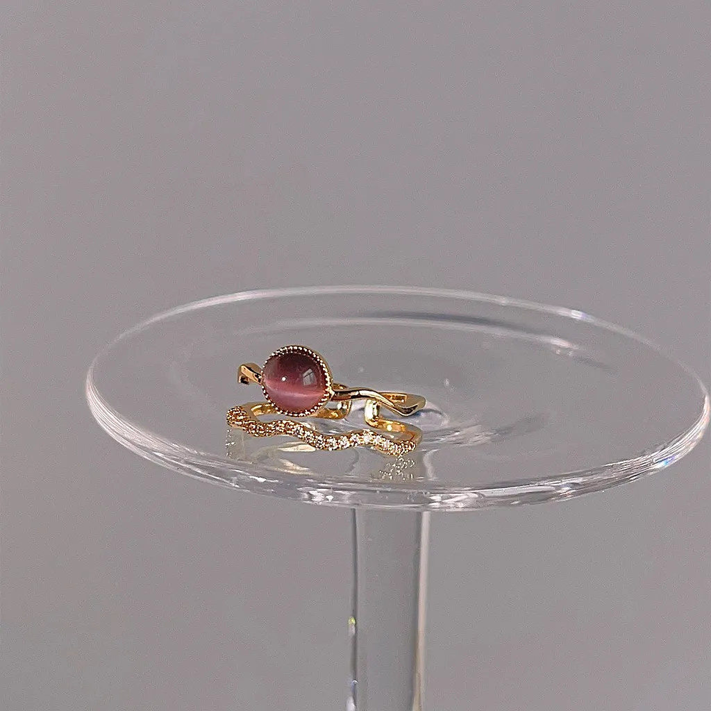 Cat's eye double-band ring resting flat on a clear glass display stand.