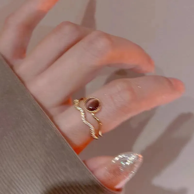 Hand wearing the gold-plated cat's eye double-band ring in warm lighting.