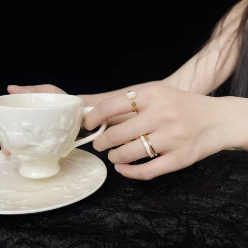 Woman wearing the gold-plated vintage cat's eye ring while holding a teacup